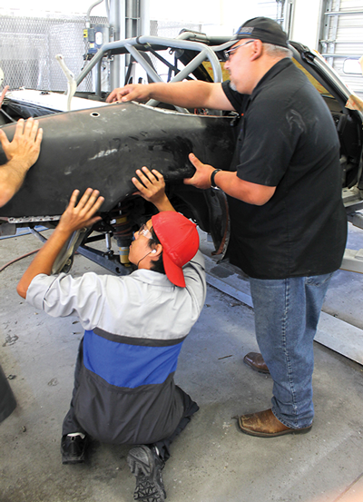 Pedraza and Salazar fit the quarter panel back onto the Miata. PHOTO BY ALEJANDRA ROSAS/THE ET CETERA