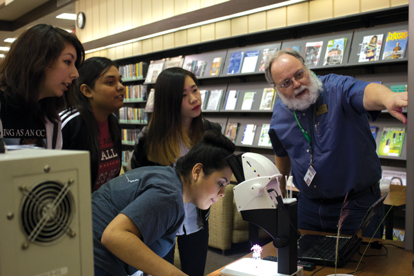 Lab coordinator Murry Gans shows students various microscopes during his Nov. 9 common book event. Photo by Andrew Gonzales/The Et Cetera