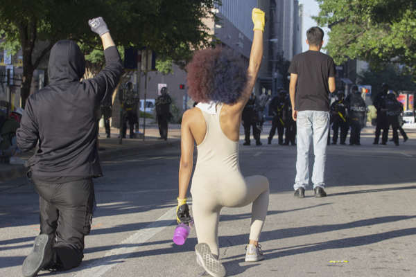 Protesters raise their fists in the air while taking a knee on Jackson Street near South Lamar Street in Dallas on May 30. Photo by Skye Seipp/The Et Cetera