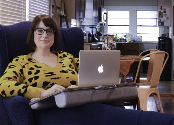 Erica Stephens works from her laptop Feb. 28 at her house, which suffered water damage and a power outage during the recent winter storm. Photo by Chantilette Franklin/The Et Cetera