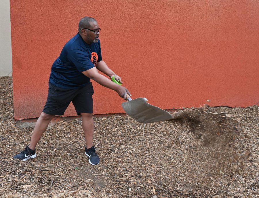 Coach Anthony Fletcher moves mulch beside the gymnasium.