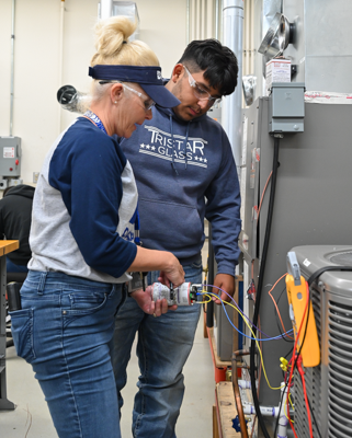 Bonnie Masten shows a student how to work on an air conditioning unit. Photo by Rory Moore/The Et Cetera