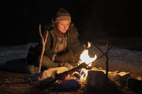 Bella Ramsey in front of campfire.