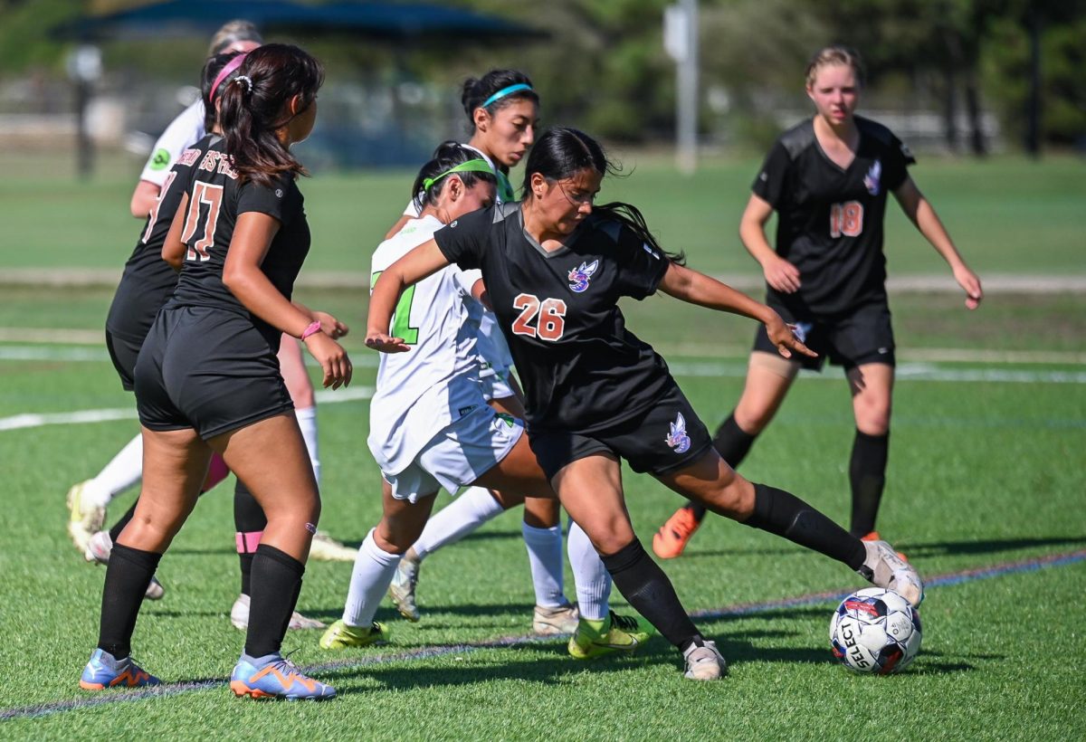 Silvia Marban struggles to keep her footing while dribbling the ball while Juliana Martinez assists.
