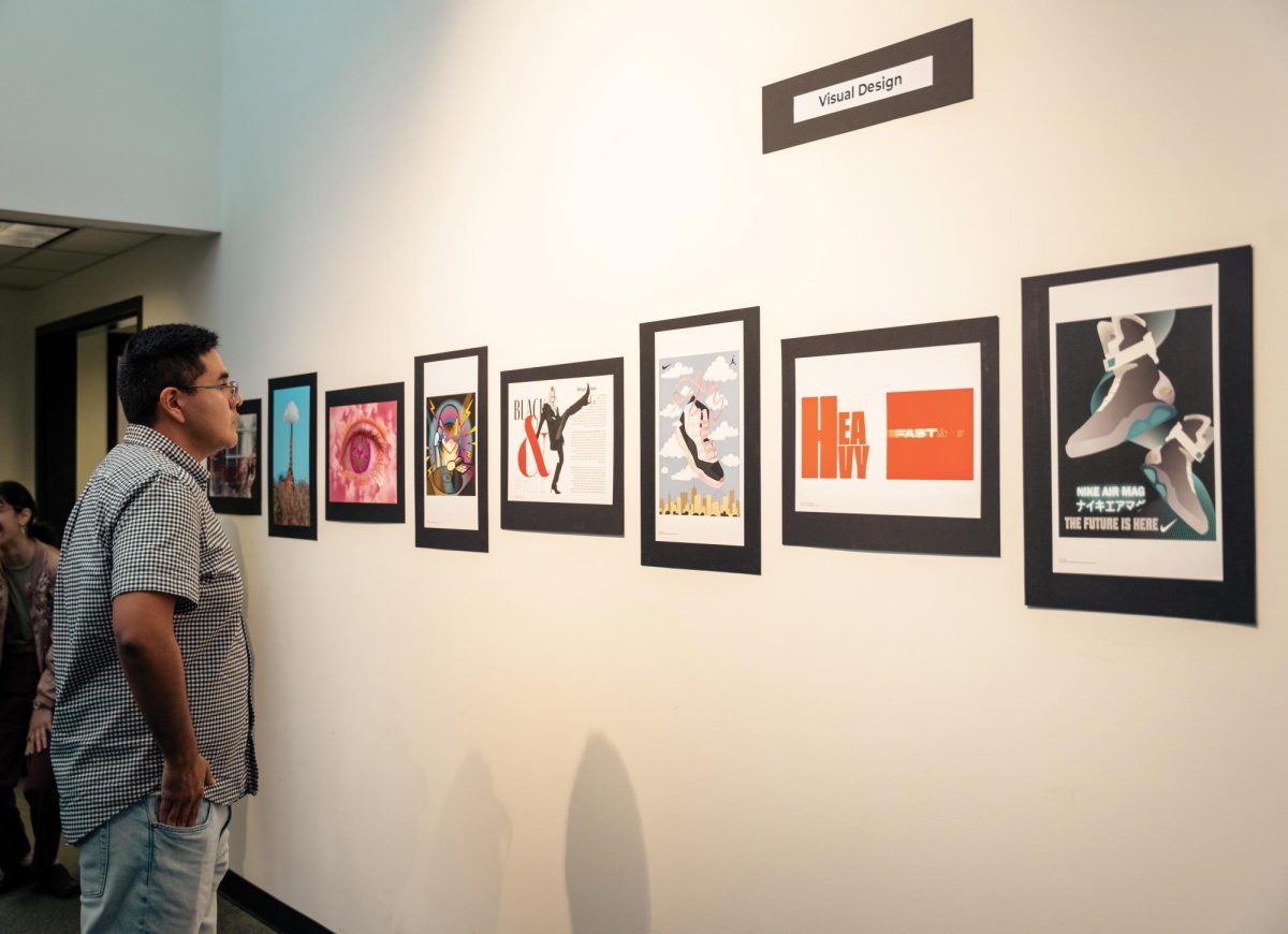 A student views visual design work featured in the showcase.